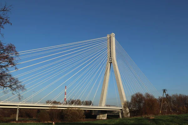 Rzeszow, Polônia - 9 9 2018: Ponte rodoviária suspensa através do rio Wislok. Estrutura tecnológica de construção metálica. Arquitetura moderna. Uma cruz branca sobre um fundo azul é um símbolo da cidade — Fotografia de Stock