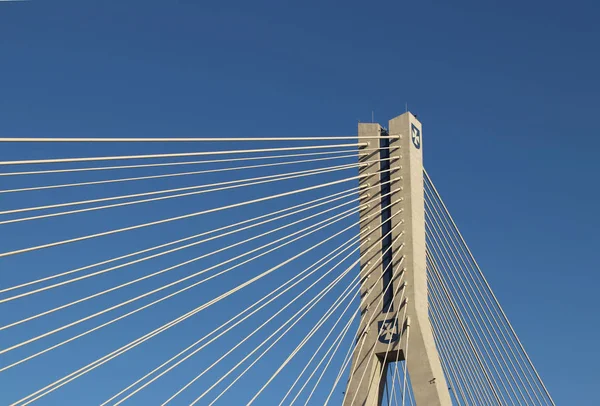 Rzeszow, Pologne - 9 9 2018 : Pont routier suspendu traversant la rivière Wislok. Construction métallique structure technologique. Architecture moderne. Une croix blanche sur fond bleu est un symbole de la ville — Photo