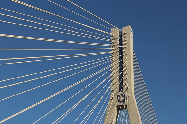 Rzeszow, Pologne - 9 9 2018 : Pont routier suspendu traversant la rivière Wislok. Construction métallique structure technologique. Architecture moderne. Une croix blanche sur fond bleu est un symbole de la ville — Photo
