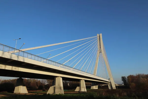 Rzeszow, Polonia - 9 9 9 2018: Ponte stradale sospeso sul fiume Wislok. Costruzione metallica struttura tecnologica. Architettura moderna. Una croce bianca su sfondo blu è un simbolo della città — Foto Stock