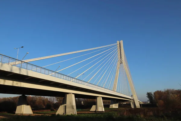 Rzeszow, Poland - 9 9 9 2018: Suspended road bridge across the Wislok River. Технологическая структура металлоконструкции. Современная архитектура. Белый крест на синем фоне - символ города — стоковое фото