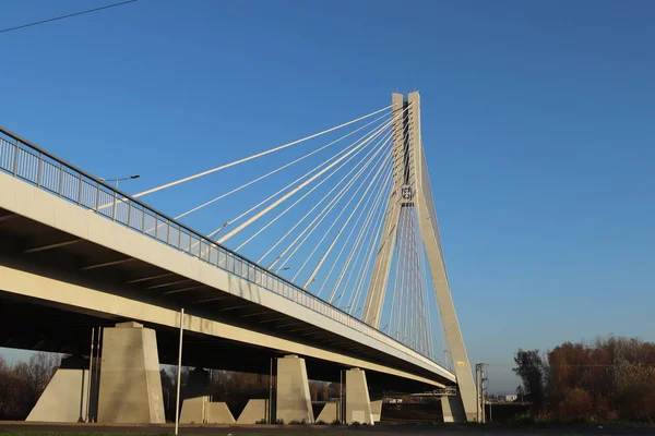 Rzeszow, Polsko - 9 9 2018: Suspendovaný silniční most přes řeku Wislok. Technologická struktura kovové konstrukce. Moderní architektura. Bílý kříž na modrém pozadí je symbolem města — Stock fotografie