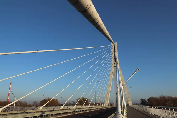 Rzeszow, Polônia - 9 9 2018: Ponte rodoviária suspensa através do rio Wislok. Estrutura tecnológica de construção metálica. Arquitetura moderna. Uma cruz branca sobre um fundo azul é um símbolo da cidade — Fotografia de Stock