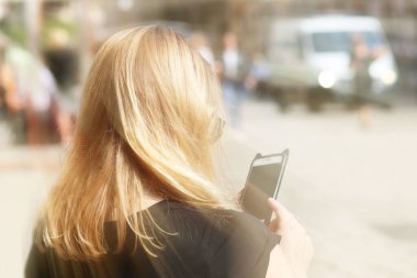 Genç güzel sarışın kız eski şehrin sokakta bir smartphone cep telefonu ile iletişim kurar. Günlük iletişimde becerikli alet. Yeni teknolojiler, modern toplumun iletişimde. Histori bir öğrenci