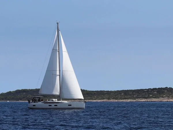 Un voilier de croisière moderne avec une plate-forme de type sloop des Bermudes passe par la côte verte de la Riviera croate par une journée d'été ensoleillée. Mer Adriatique de la région méditerranéenne. District de Dalmatie — Photo