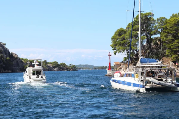 Sailing catamaran sails along the rocky green coast past the red literary sign - the fairway lighthouse. City of Sibenik in the Dalmatia region in Croatia. Adriatic sea in the Mediterranean area