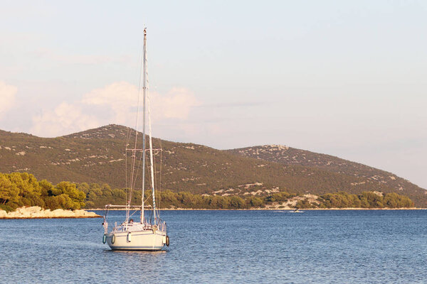 A sailing yacht is anchored in a bay. People bathe in the sea. Active rest on the Adriatic Sea of the Mediterranean region. Dalmatian riviera of Croatia. Prestigious and rich lifestyle