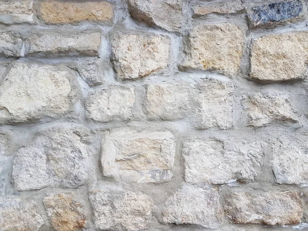 Ancient medieval stone masonry. Texture of a fragment of a wall of an old structure. A background for design and creative work. Decoration and exterior decoration of the building. Construction works — Stock Photo, Image