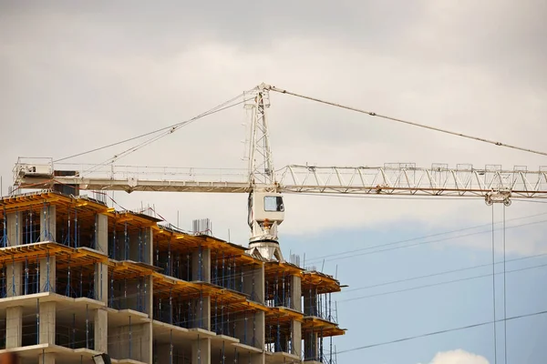 Gru a torre lavorano durante la costruzione di un edificio a più piani. Nuovi appartamenti per residenti e locali per uffici. Lavoro rischioso in quota. Sollevamento di materiali da costruzione pesanti. Sviluppo urbano — Foto Stock