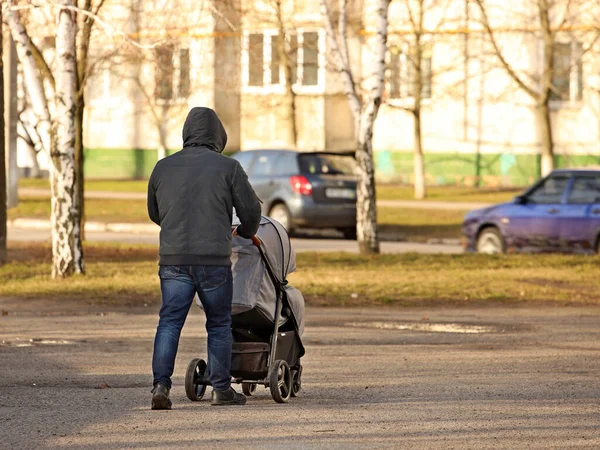 一个男人把婴儿车推到他面前 父亲带着一个孩子在附近散步 父母关心年轻一代的成长 婴儿的户外睡眠 负责任的父亲 — 图库照片