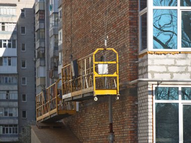 İnşaat, çok katlı bir binanın ön cephesi olan robotlar için askıya alındı. Yükseklerde güvenlik işi. İşçiler için asansör kullanan binaların yapımı. İnsanları canlandırmak için..