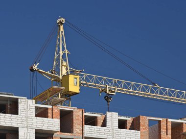 Tulumlu iki vinç operatörü, çok katlı bir binanın inşaatı sırasında çalışan yüksek katlı bir vinç tamir ediyorlar. Yüksekken riskli iş. Ağır inşaat malzemeleri kaldırılıyor. Şehir Geliştirme.