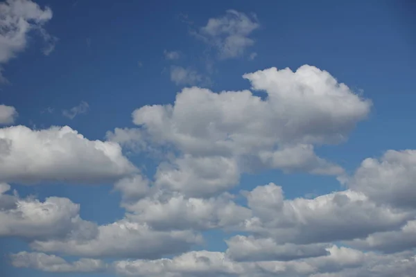 The sun shines through the cumulus clouds in the blue sky. Background and texture for artists and design. Bright light in the eyes. Water in gaseous state. The circulation of fluid in nature.