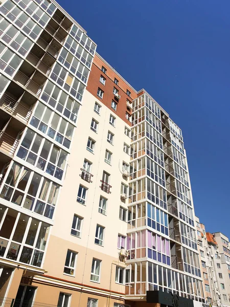 Lviv, Ukrajna - 3 4 2020: Magas, többszintes modern ház homlokzata erkéllyel és nagy üvegablakokkal. Modern építészet tervezése. Legfelülnézetből alulról. Modern városi építészet — Stock Fotó