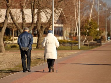 İskandinav yürüyüşü için sopaları olan yaşlı bir çift. Emeklilerin sağlıklı ve aktif yaşam tarzı. Aile açık hava eğlencesi. Sağlık, metabolizmayı hızlandırmak ve kilo vermek için yürüyor. Mutlu yaşlılar..