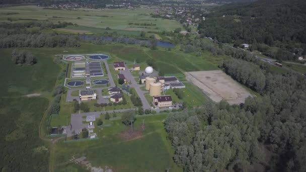 Čistírna městských odpadních vod. Letecká fotografie čistíren odpadních vod umístěných v krásném zeleném kopcovitém terénu. Recyklace lidského odpadu. Otázka čisté pitné vody — Stock video