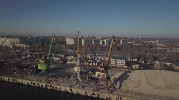 Grote havenkranen aan de oever bij de pier laden de truck met rivierzand en een grote afvalberg. Een trein voor het vervoer van bulklading. Het werk van de vrachthaven. Luchtdrone quadrocopter — Stockvideo