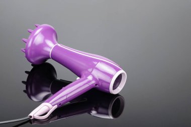 Gri ayna arka planda difüzörlü pembe saç kurutma makinesi