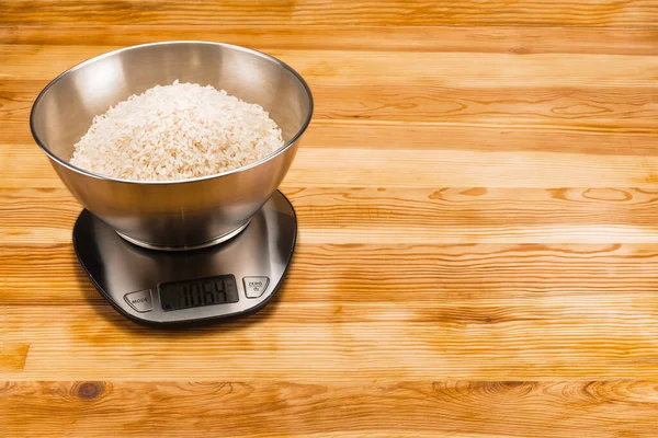 Рис в миске в электронном масштабе на деревянном фоне с ко — стоковое фото