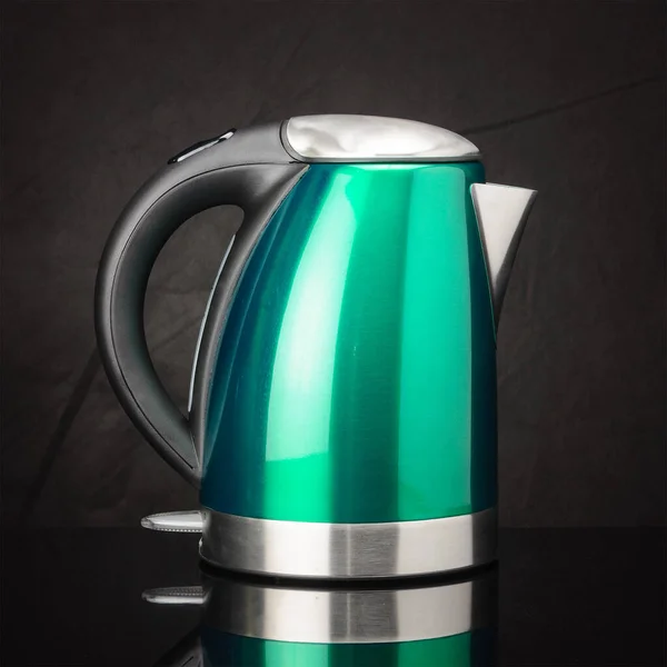 Green stainless steel kettle on black mirror background