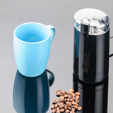 Gri ayna arka üzerinde kahve fasulyesi ve kupa ile çay değirmeni