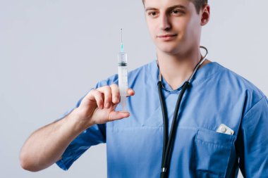 Beyaz arka planda izole edilmiş enjeksiyon için şırıngaya bakan odaklanmış genç doktor portresi