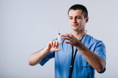 Beyaz arka planda izole edilmiş enjeksiyon için şırıngaya bakan odaklanmış genç doktor portresi