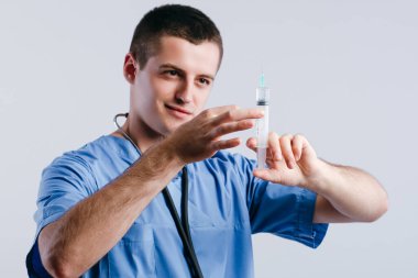 Beyaz arka planda enjeksiyon için şırınga tutan ciddi genç doktor portresi.