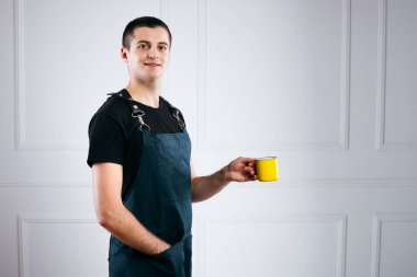 Garson, önlük giymiş kahve servisi yapıyor. Yeşil önlüklü garson. Müşteri için sarı kahve tutuyor.