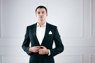 Smokinli zarif genç işadamının portresi ceketini düzeltiyor.