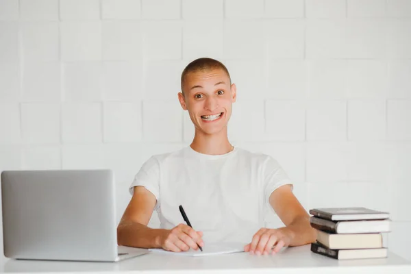 Νεαρός Χαμογελαστός Μαθητής Κάθεται Στο Λάπτοπ Και Διαβάζει Απομονωμένα Λευκό — Φωτογραφία Αρχείου