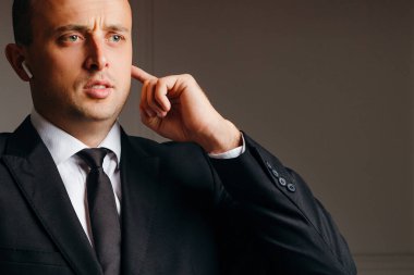 şaşırmış iş adamı telefonda kulaklıkla konuşuyor.