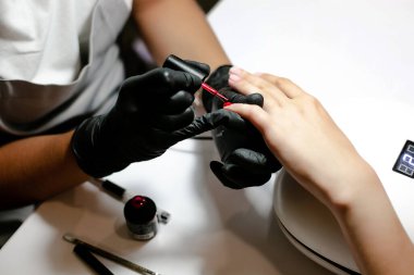 Kadın manikürcü güzellik salonunda manikür yaparken tırnaklarını törpülüyor ve şekillendiriyor.