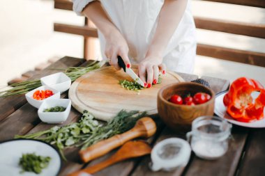 Tahta bir tabakta yeşil soğan doğrayan bir kadının elleri. Guacamole yapıyorum.