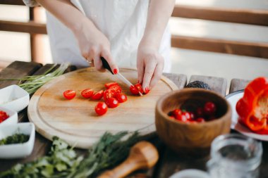 Kadının elleri kiraz domateslerini ahşap bir tabakta kesiyor. Guacamole yapıyorum.
