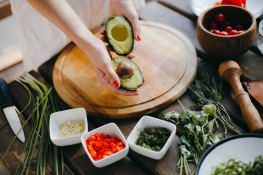 Avokadoyu ikiye bölen kadın elleri. İki avokado yarım guacamole yapmak için hazır