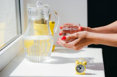 Bir bardak suyla bir kadının elleri.