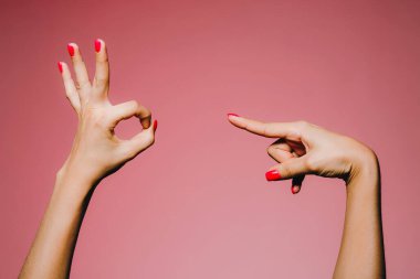 Pembe arka planda izole edilmiş parlak manikürlü bir kadının elleri daireyi işaret ediyor.
