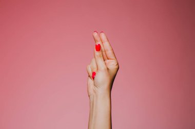 Woman's snapping hand with bright manicure isolated on pink background clipart