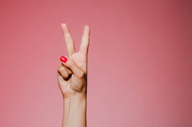 Pembe arka plan barış jestine izole edilmiş parlak manikürlü kadınların elleri.