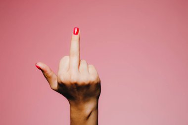 Pembe arka planda izole edilmiş, parlak manikürlü bir kadının elleri uzaklaşma işareti.