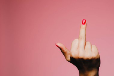 Pembe arka planda izole edilmiş, parlak manikürlü bir kadının elleri uzaklaşma işareti.