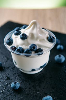 Etrafında böğürtlenlerle plastik bardaklarda yapılan yaban mersinli dondurma.