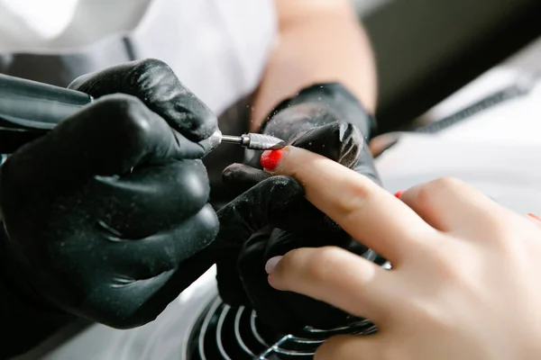美容院五金修指甲的闭锁 美容师正在用电钉档案钻对女性手指进行美甲修整 把美甲架摘下来 — 图库照片