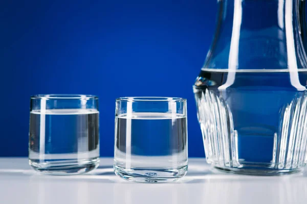 Jarro Vidro Água Dois Copos Isolados Fundo Azul — Fotografia de Stock