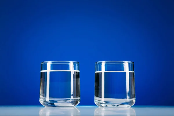 Dois Copos Água Isolados Sobre Fundo Azul — Fotografia de Stock