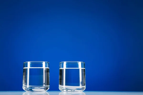 Dois Copos Água Isolados Sobre Fundo Azul — Fotografia de Stock