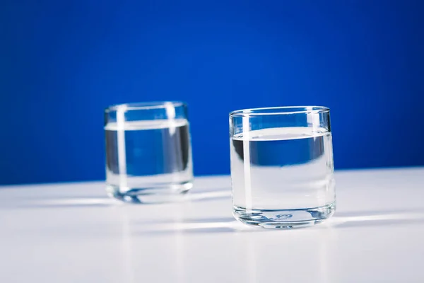 Dois Copos Água Isolados Sobre Fundo Azul — Fotografia de Stock