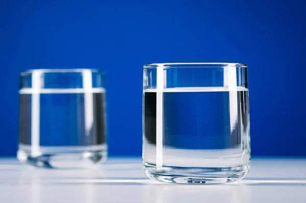 Dois Copos Água Isolados Sobre Fundo Azul — Fotografia de Stock