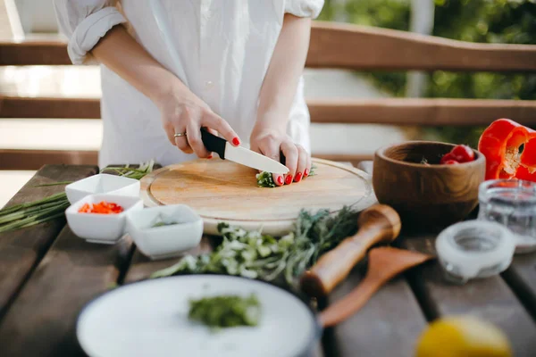 Tahta bir tabakta yeşil soğan doğrayan bir kadının elleri. Guacamole yapıyorum.